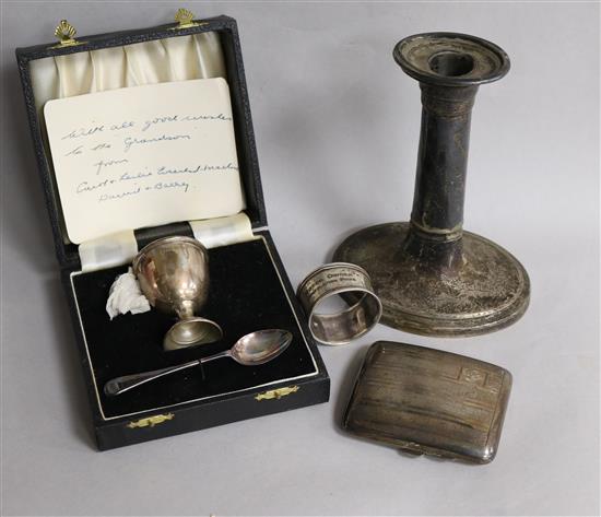 A silver egg cup and spoon, a cigarette case, a 19th century silver candlestick and a napkin ring.